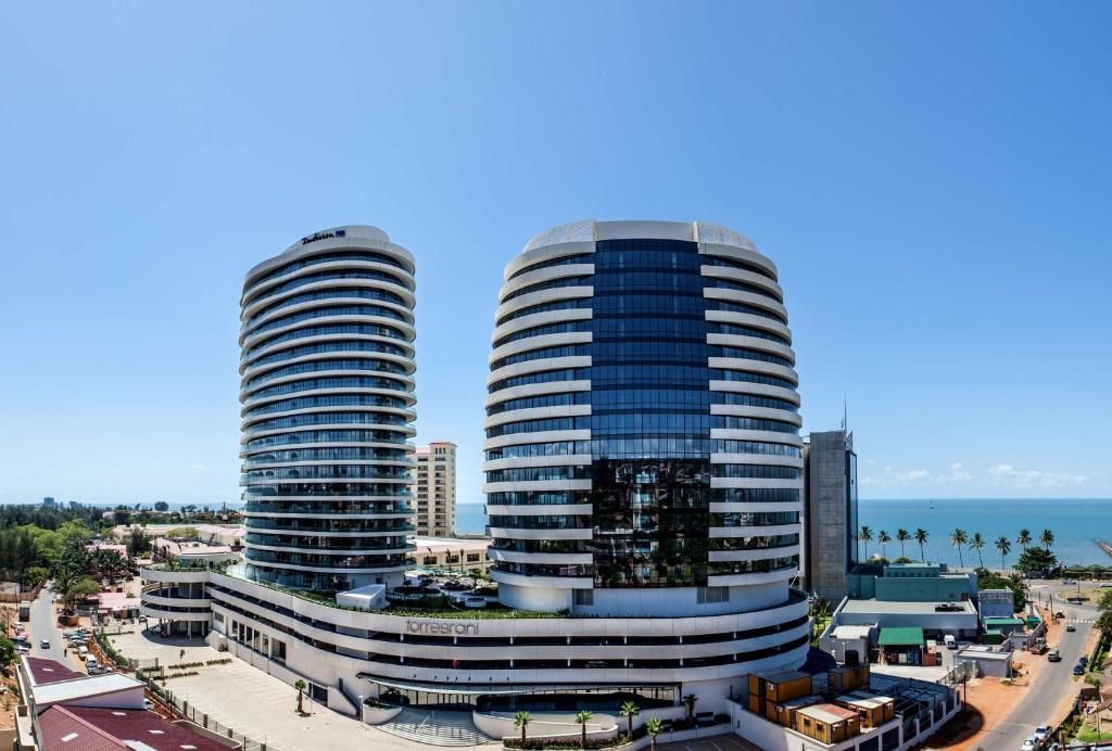 Modern twin high-rise buildings by the waterfront under a clear blue sky