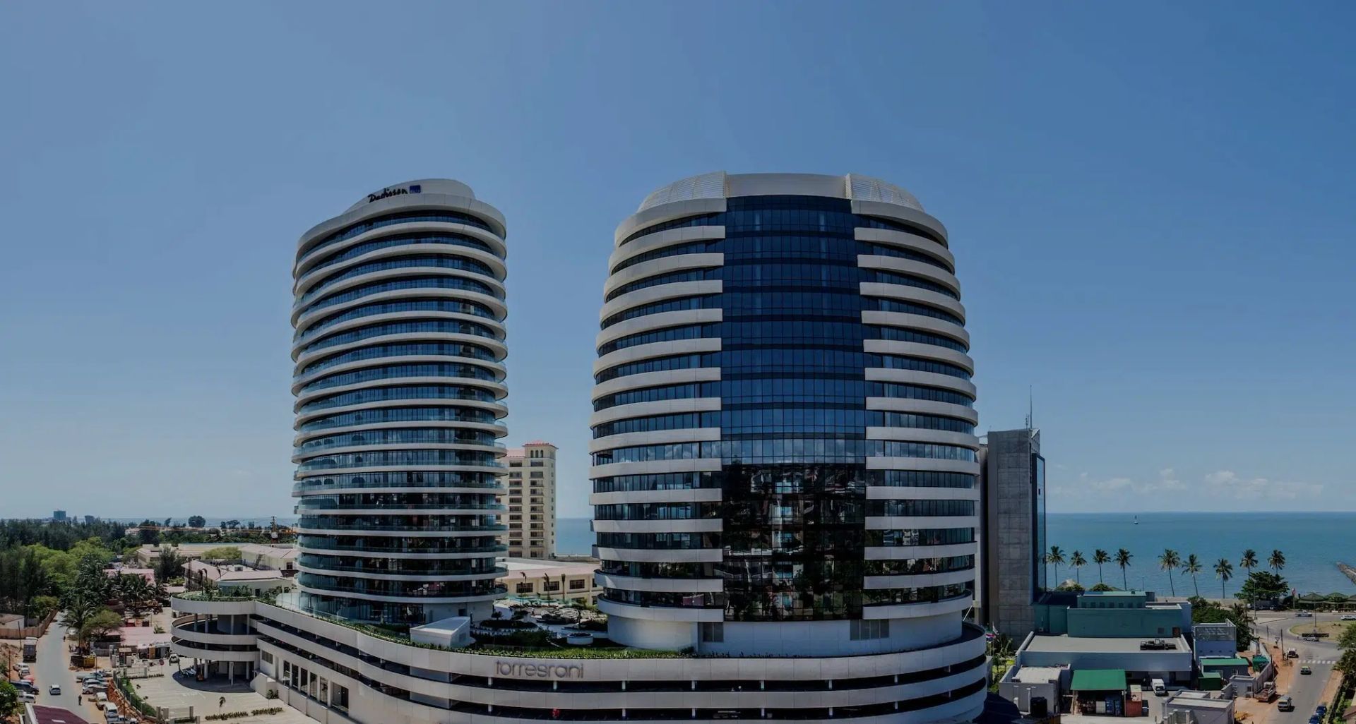 Two modern beachfront high-rises by the sea under a clear blue sky