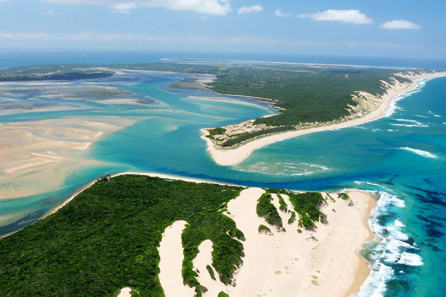 Aerial view of a tropical island with white sand beaches, turquoise water, and green vegetation