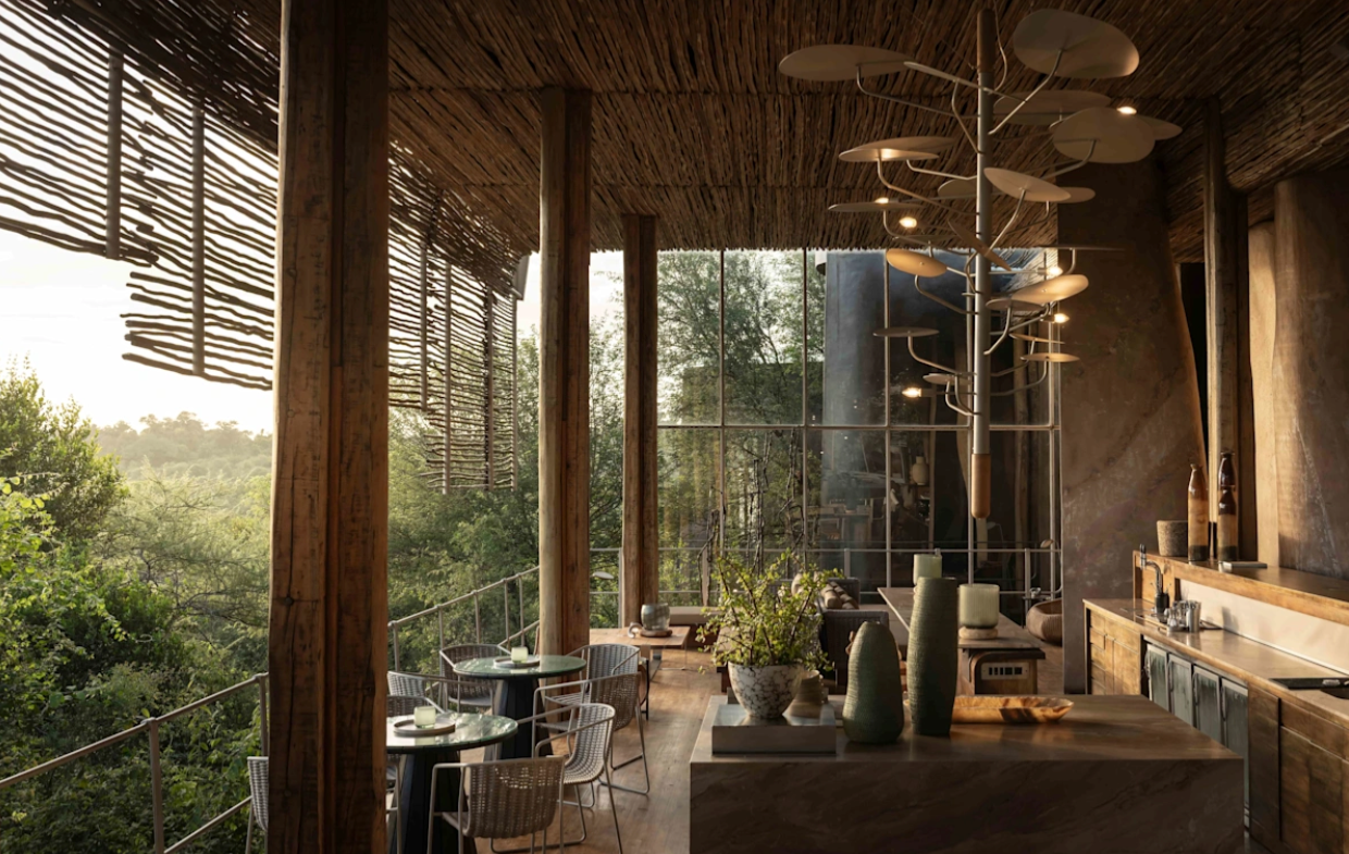 Sunlit rustic café with wooden beams, hanging lights, and tables overlooking greenery