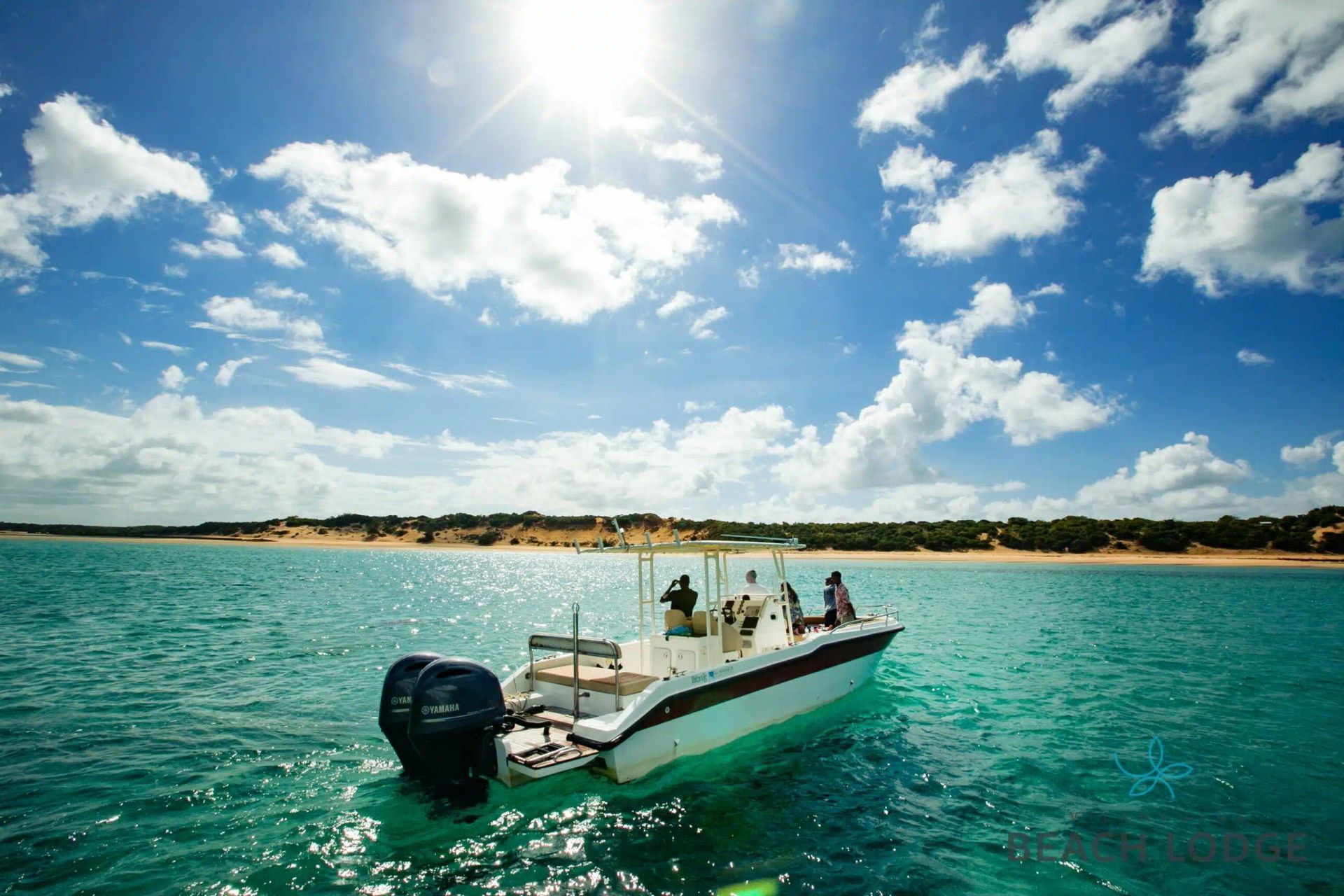 Small motorboat on turquoise water under a bright blue sky with scattered clouds