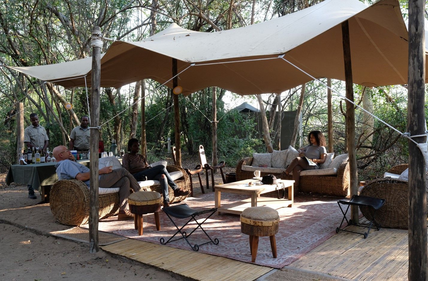 Wild Camp Gorongosa is a modern, luxury outdoor lodging experience featuring canvas tents and beds with fine linens, solar lighting, solar showers, ablutions, USB ports for charging phones, evening campfires, and an outdoor dining area.