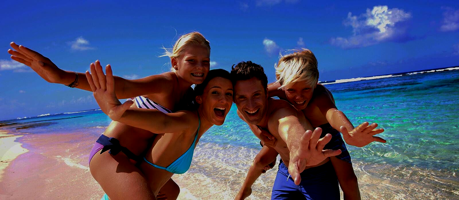 Friends posing playfully on a sunny beach with turquoise water and blue sky