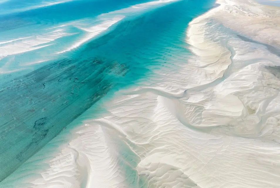 Aerial view of turquoise ocean water flowing through white sandbars.