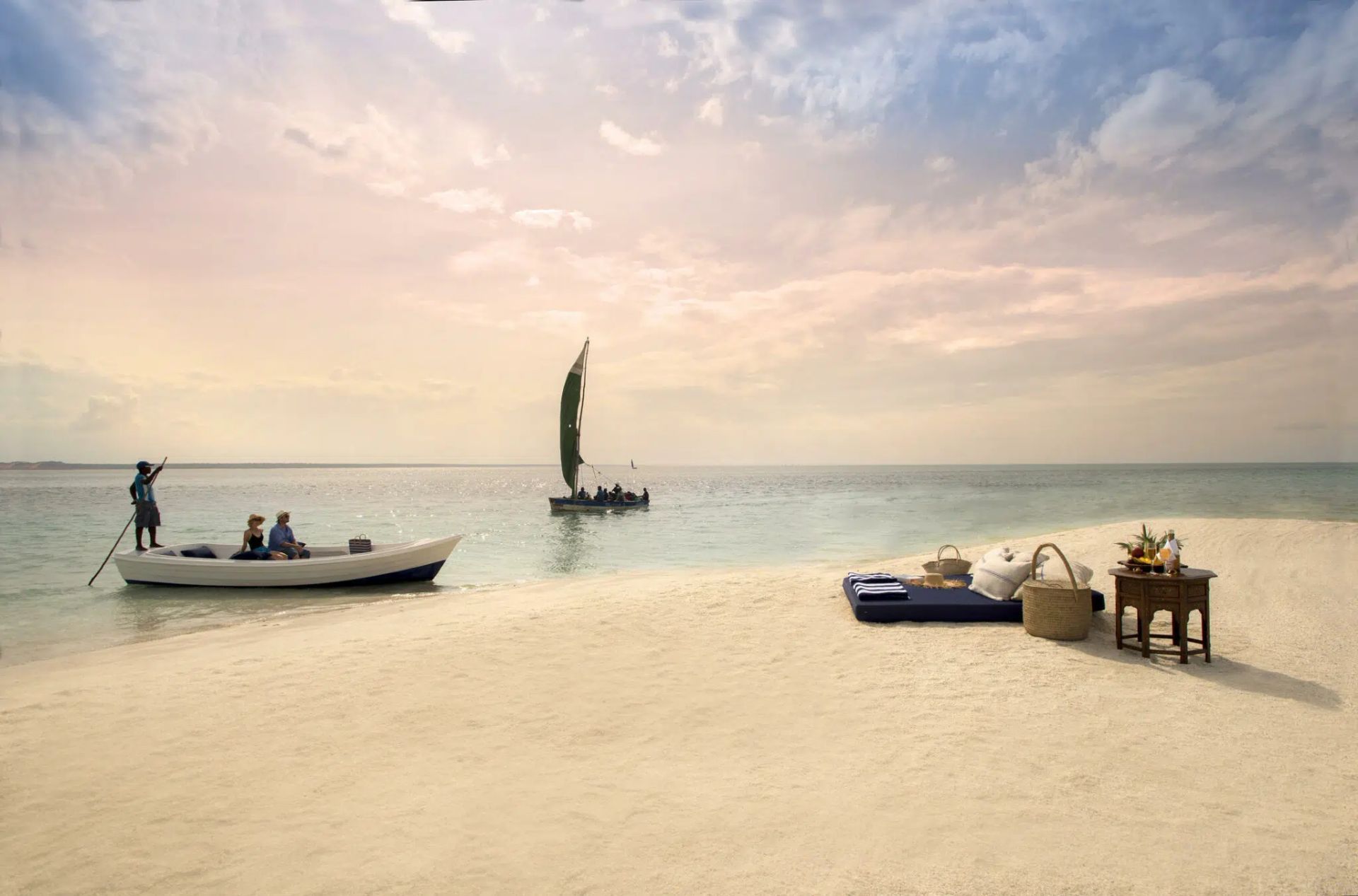 Sunny beach with a small boat, sailboat, and lounge chairs on white sand by calm sea