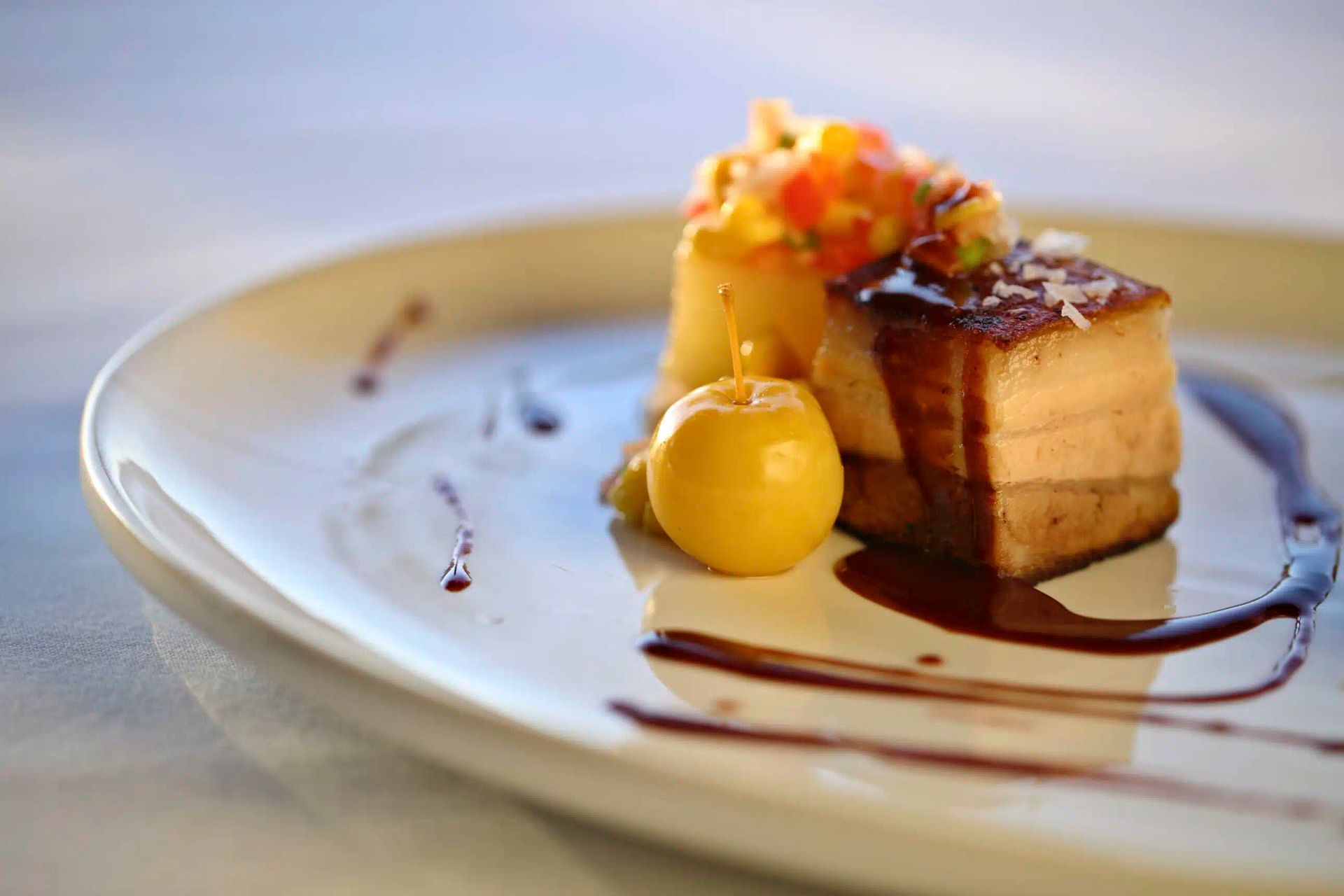 Dessert plate with a layered cake, fruit garnish, and chocolate sauce swirls