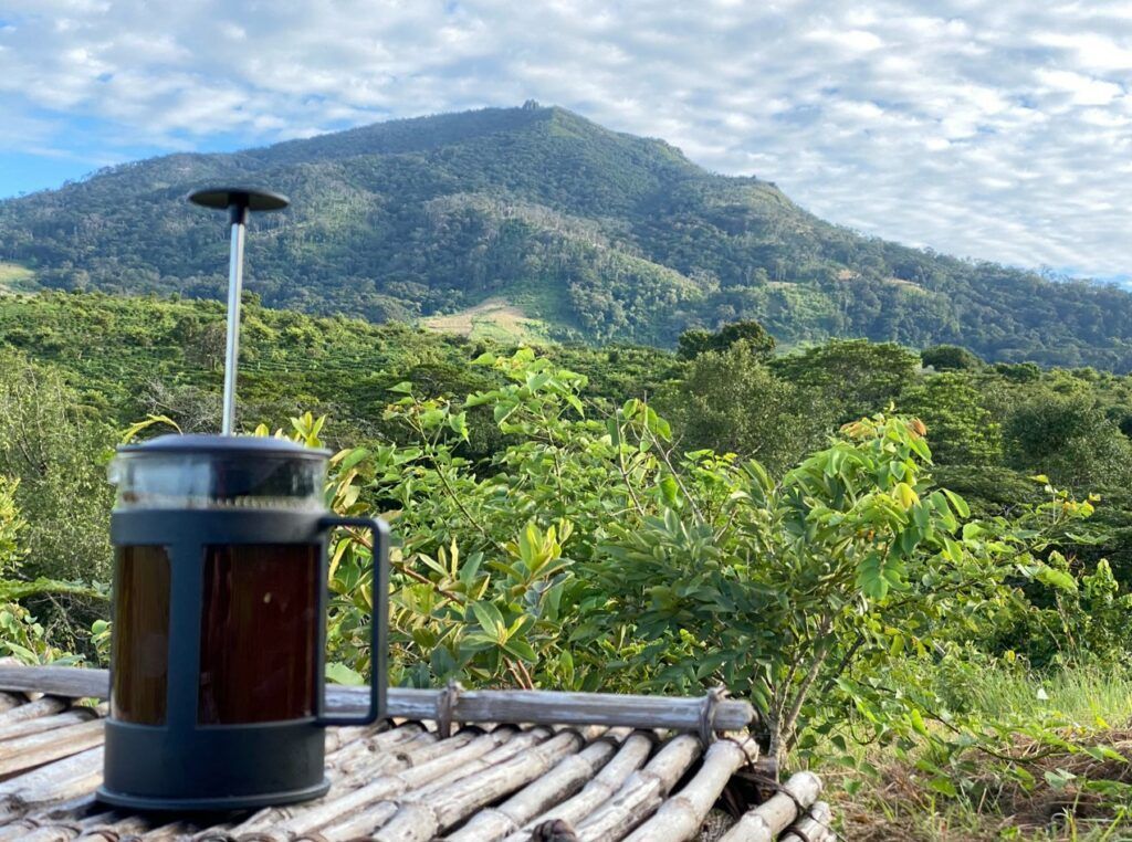 Bamboo patio table with a French press overlooking a lush green mountain landscape
