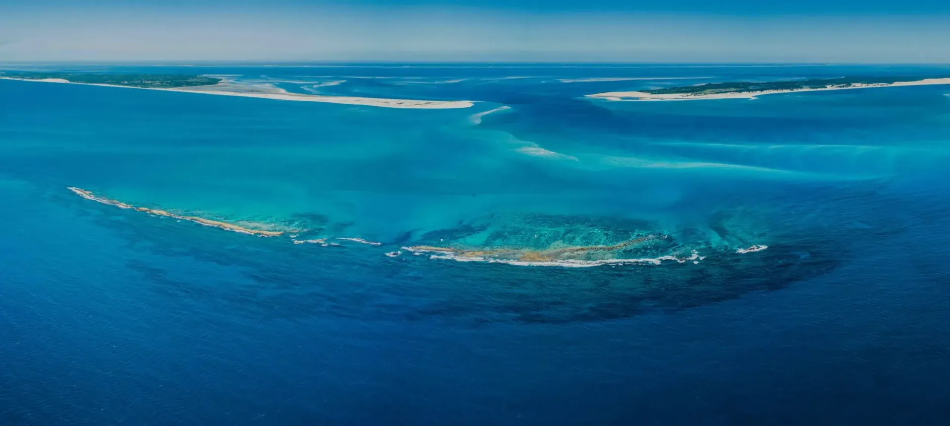 Aerial view of a turquoise coral reef surrounded by deep blue ocean water