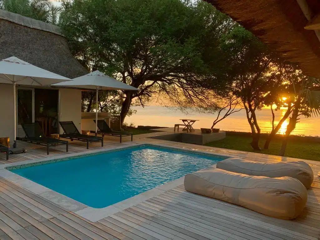 Poolside patio with lounge chairs and sunset view over water