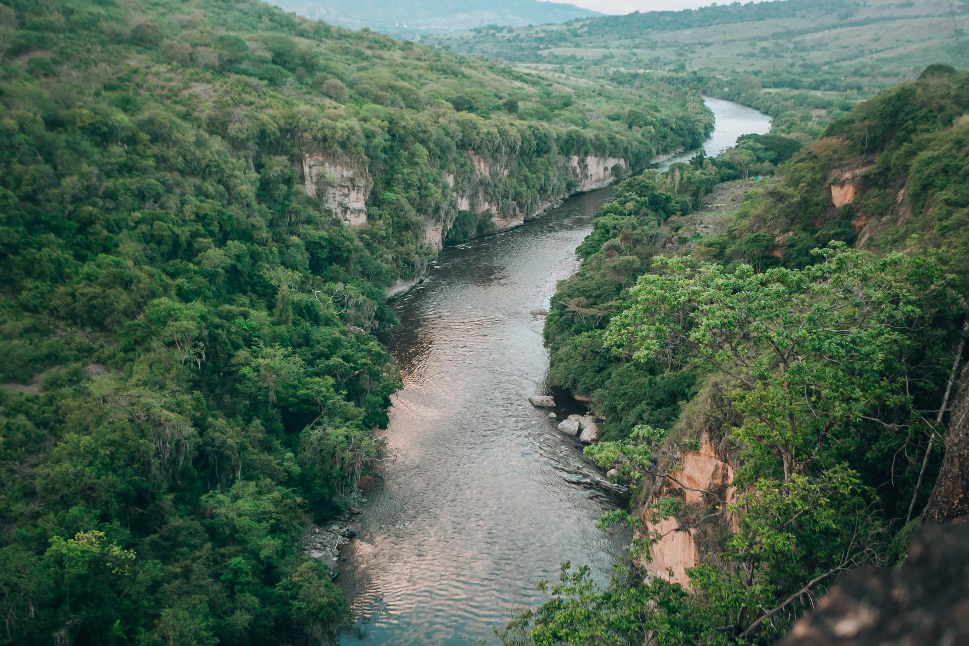 A winding river through lush green cliffs and forested valley.