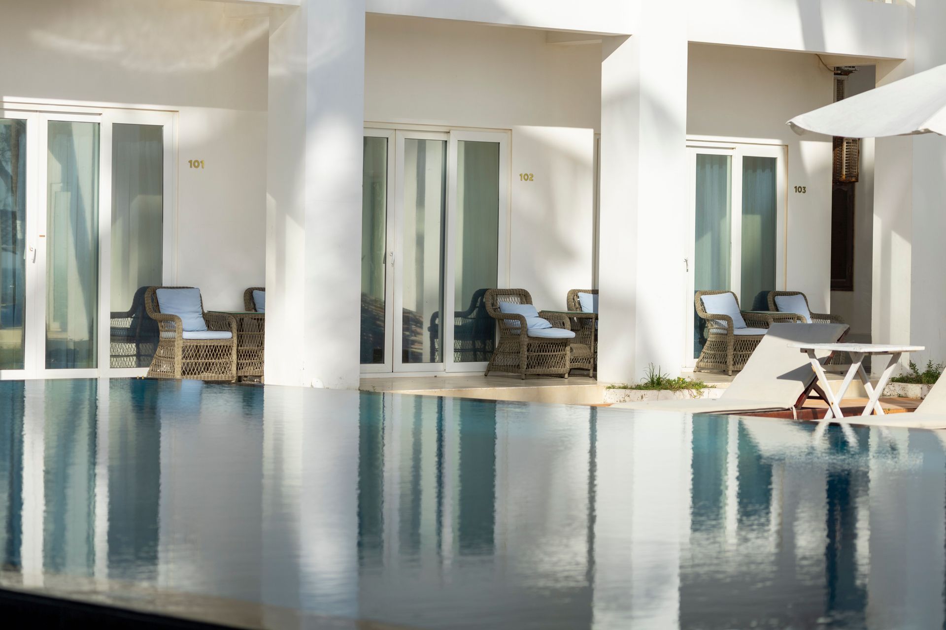 Modern hotel poolside with white cabanas, lounge chairs, and turquoise water reflecting sunlight