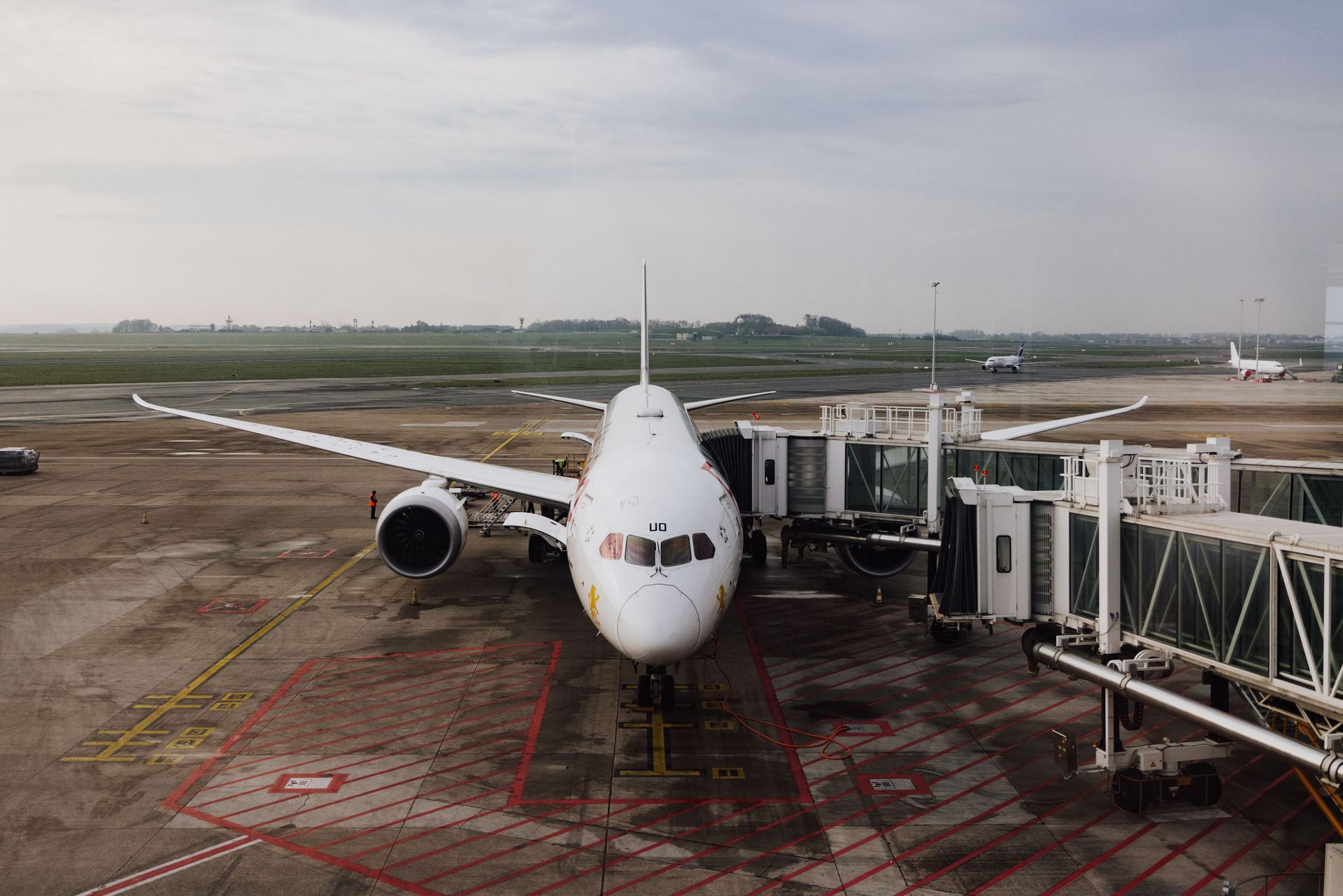 Commercial airplane parked at an airport gate on a wet tarmac, viewed from the front.