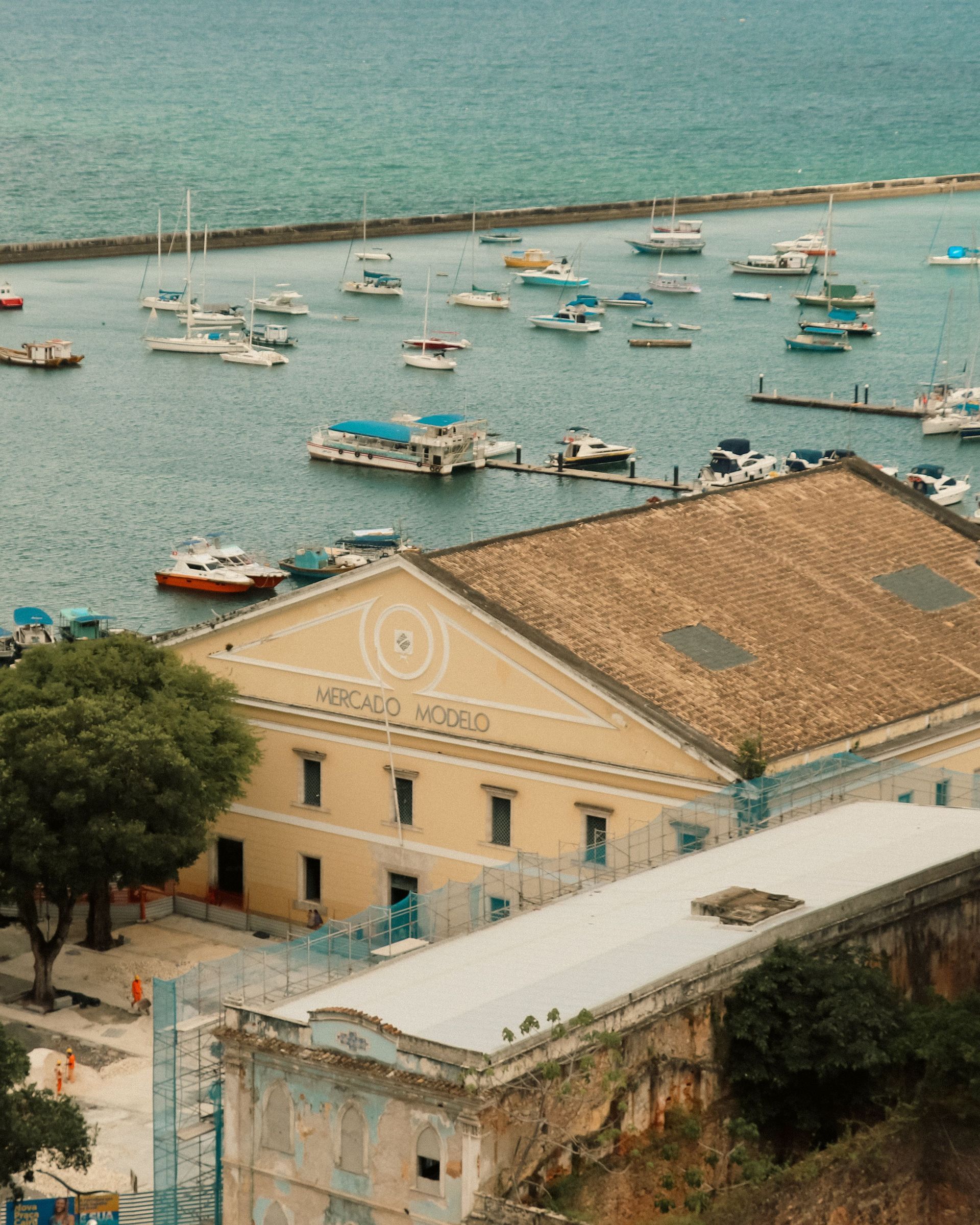 Harbor with many small boats and a beige-roofed waterfront building beside blue water