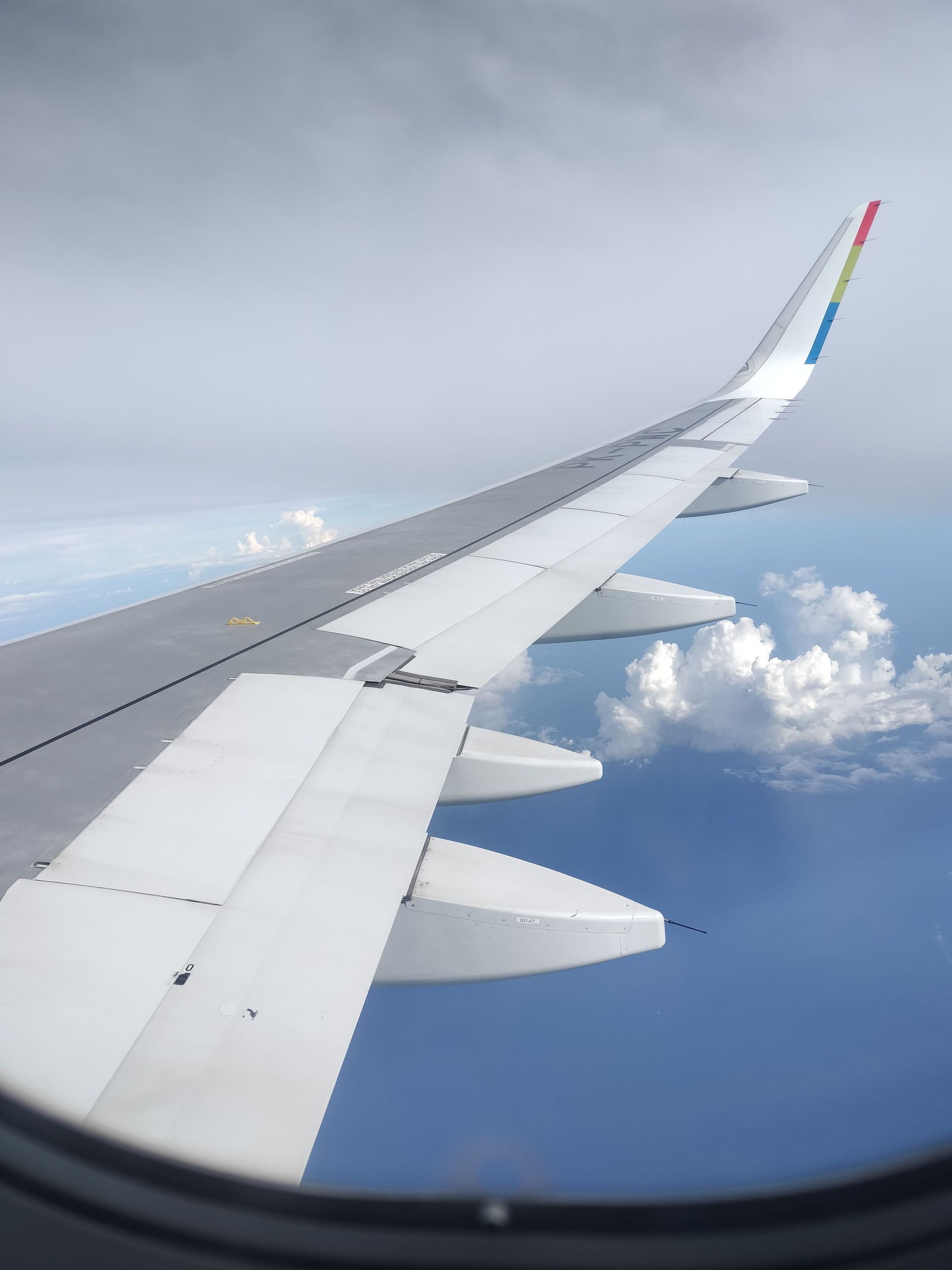 Airplane wing above clouds, viewed from a window