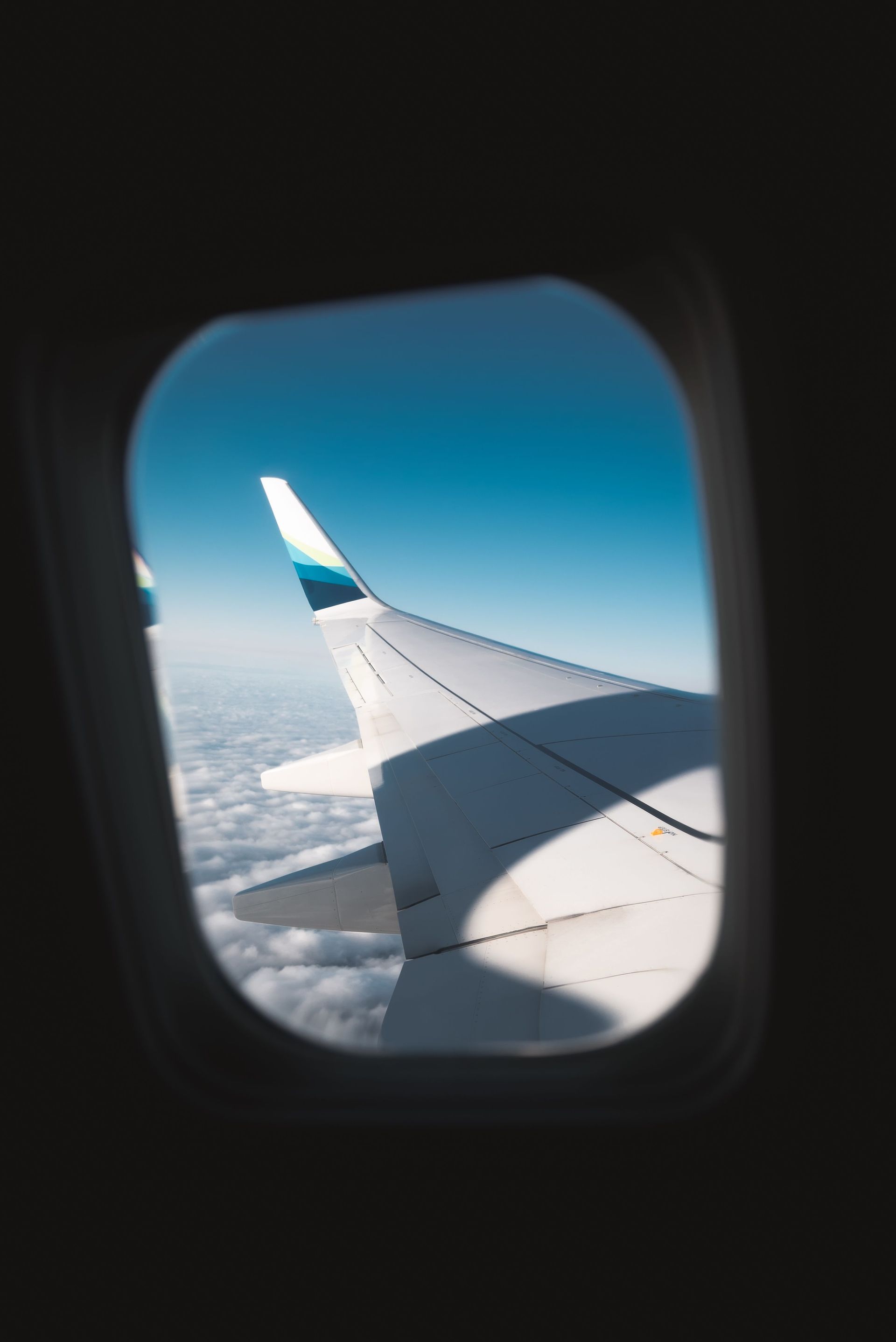 Airplane wing seen through a window above the clouds at sunset