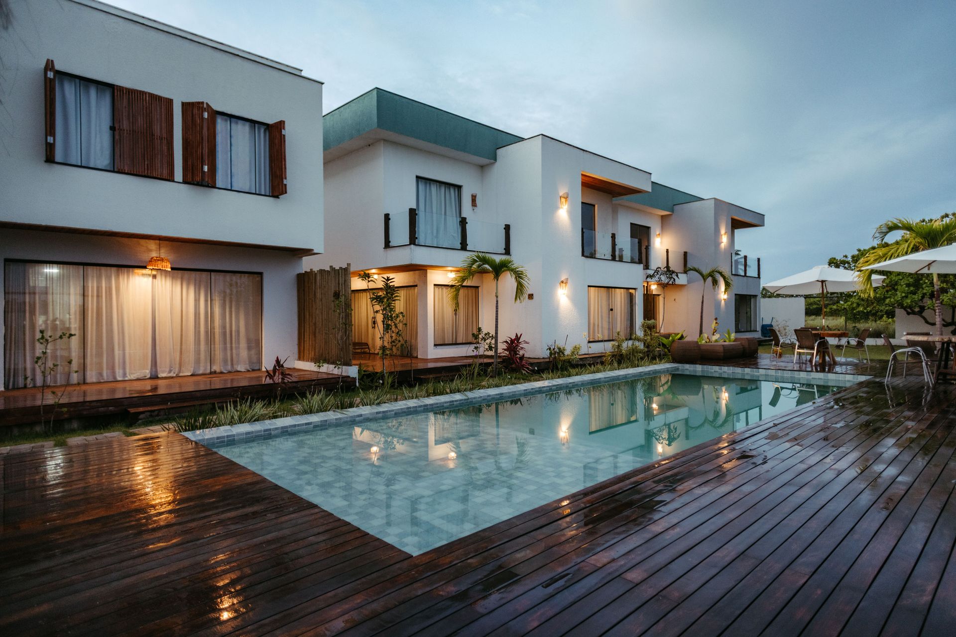 Luxury white villa with a turquoise pool and outdoor dining terrace by the water