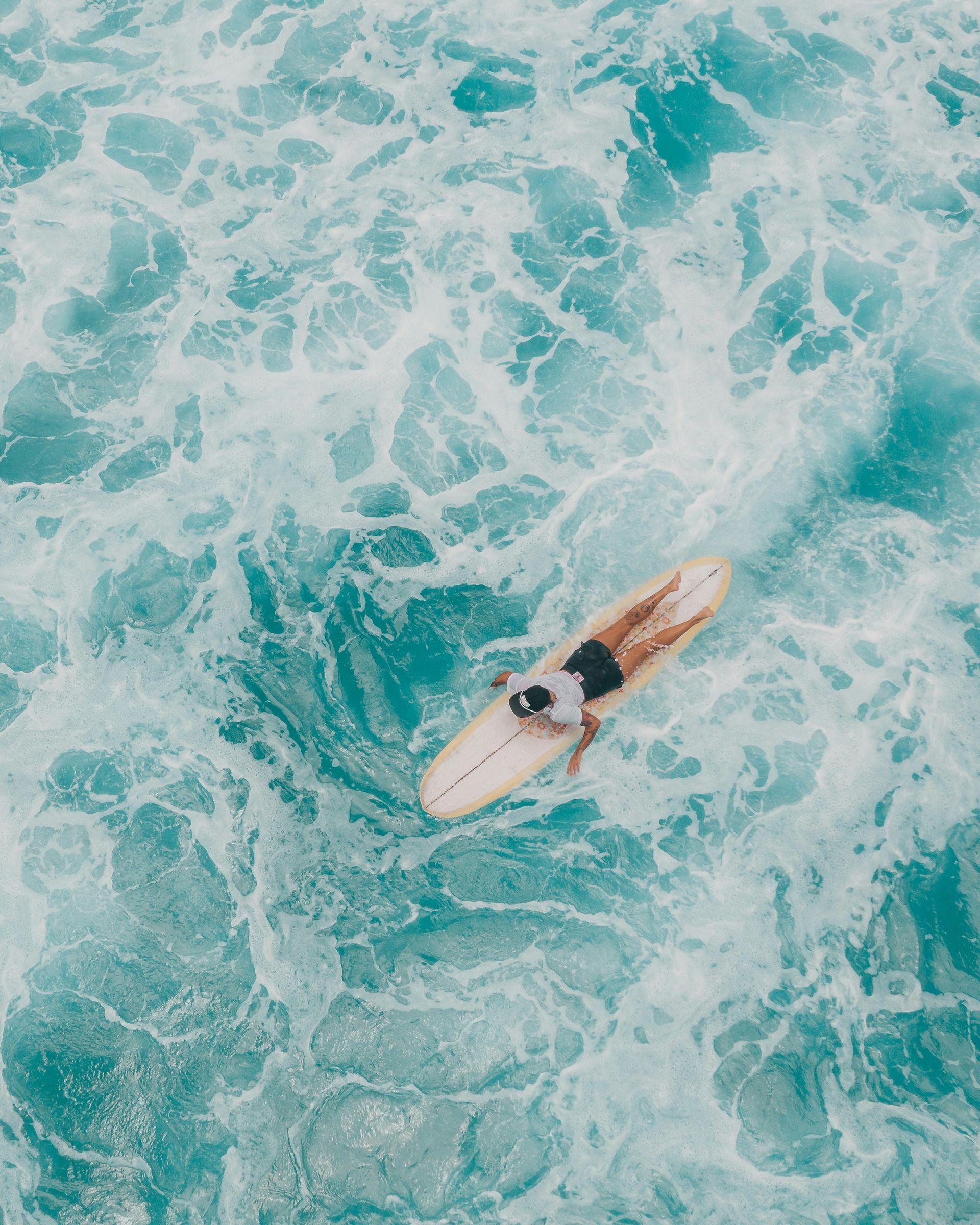 Surfer on a white board in turquoise, foamy ocean water