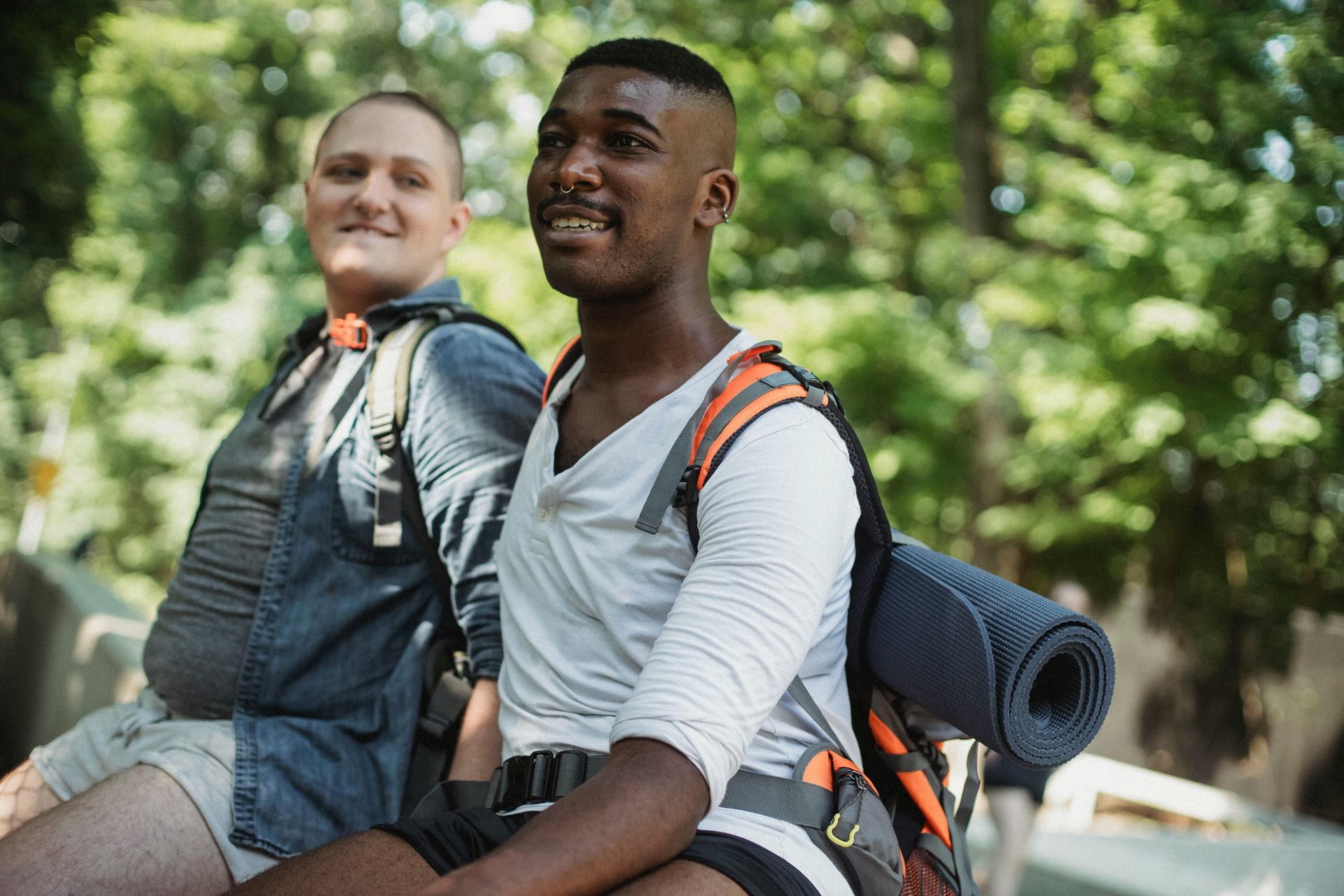 Two hikers with backpacks smiling on a forest trail