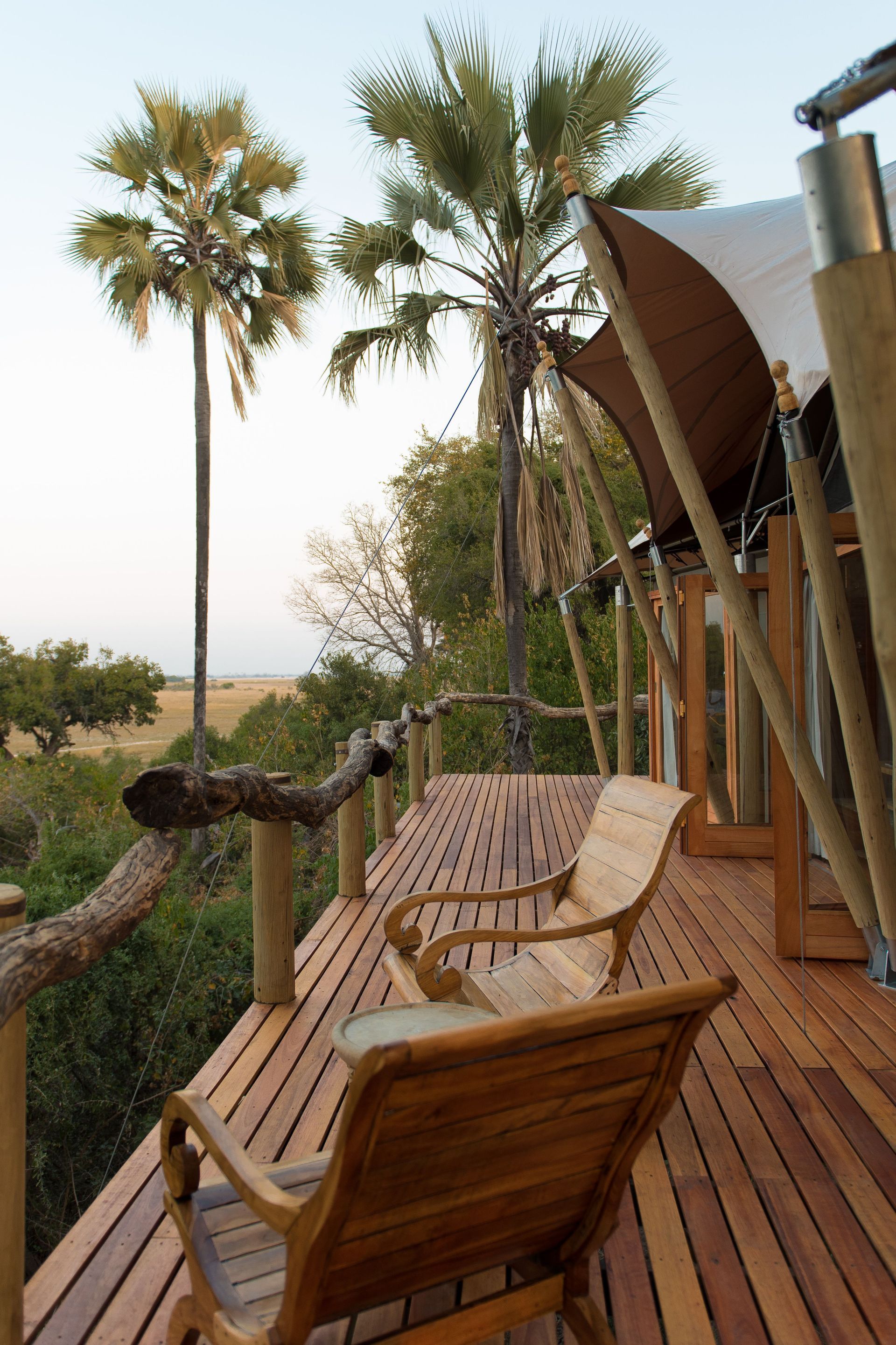 Wooden deck with lounge chairs overlooking palm trees in a tropical setting