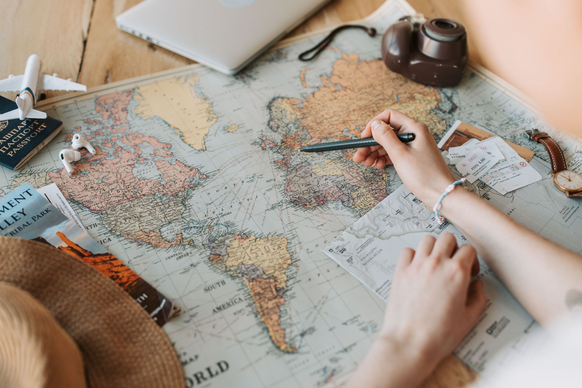Hands marking locations on a world map with a pen and notes beside it