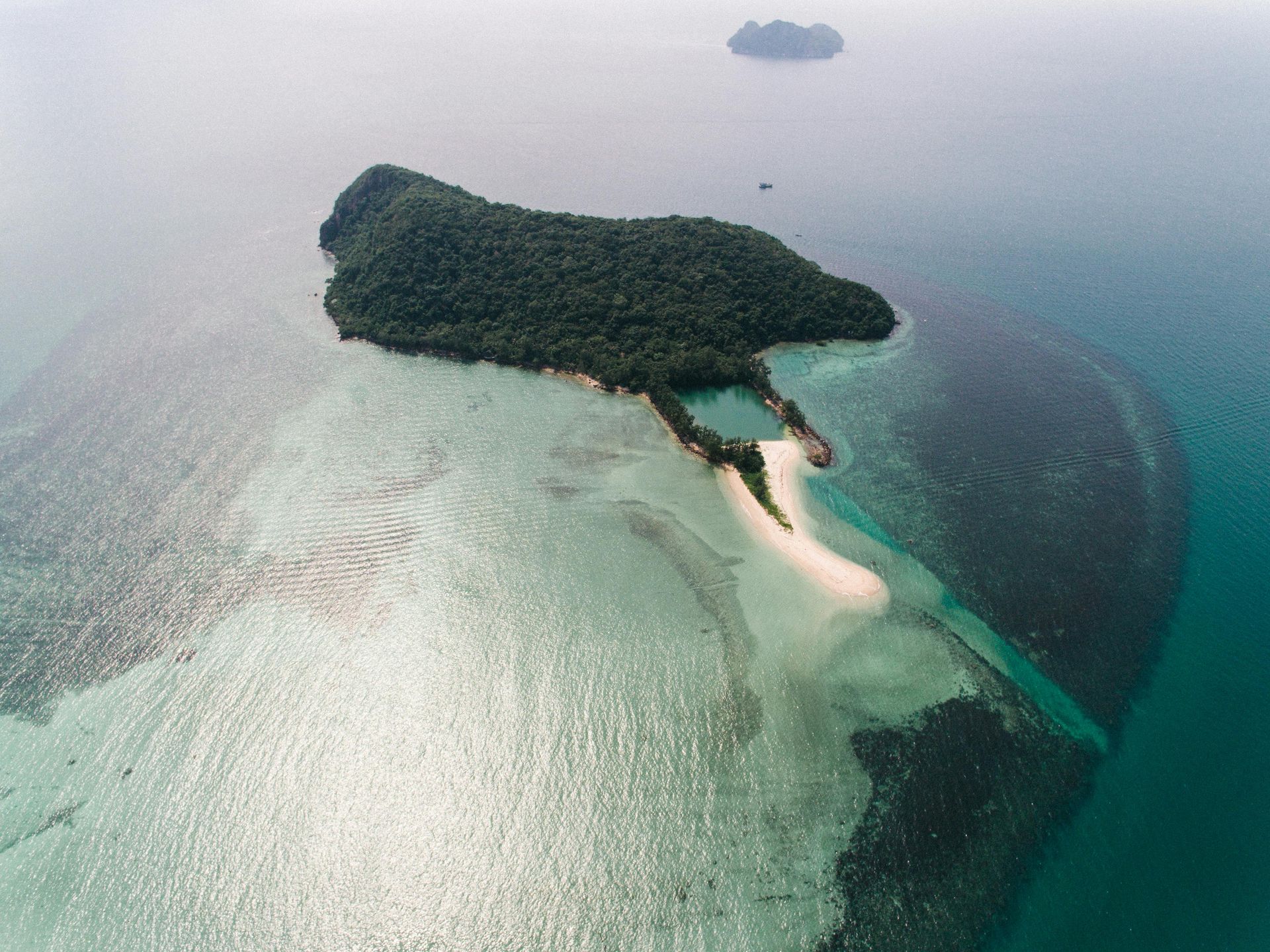 Aerial view of a lush tropical island with white sandbars and turquoise water.