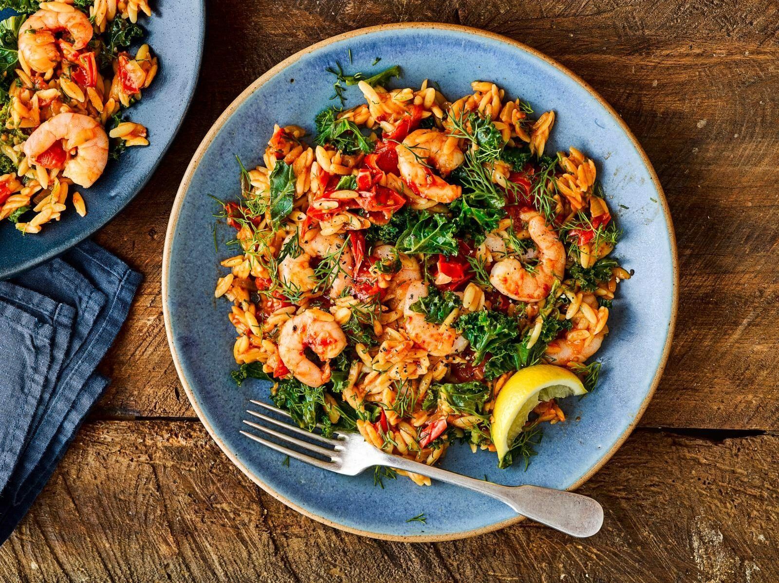 Shrimp and herb rice on blue plates with lemon wedges, served on a wooden table