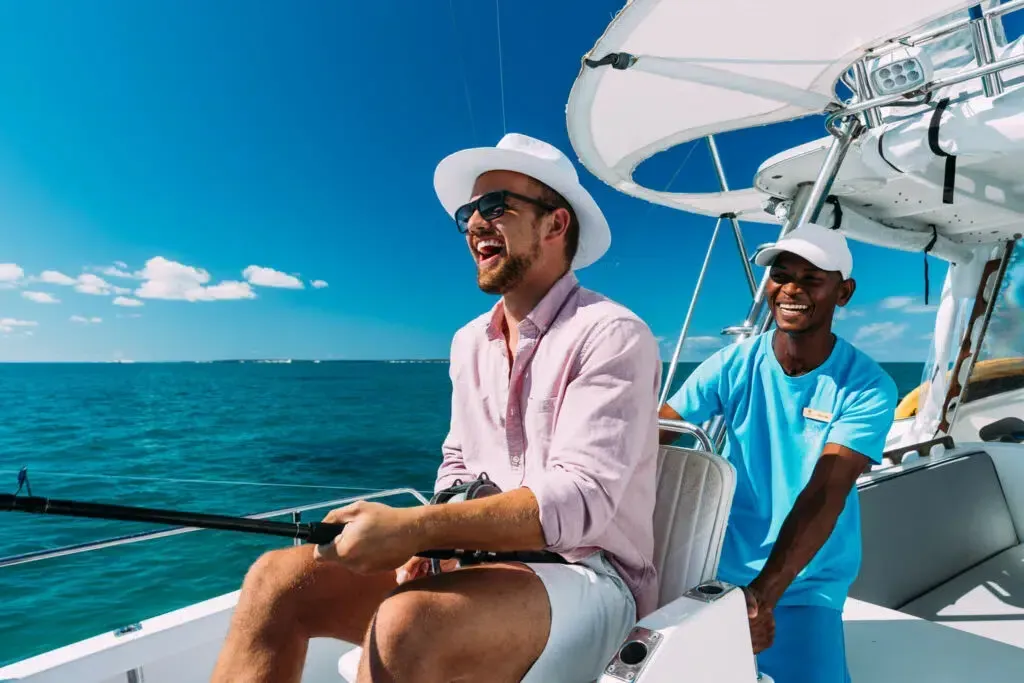 Two people sailing on a boat, smiling on a sunny blue ocean.