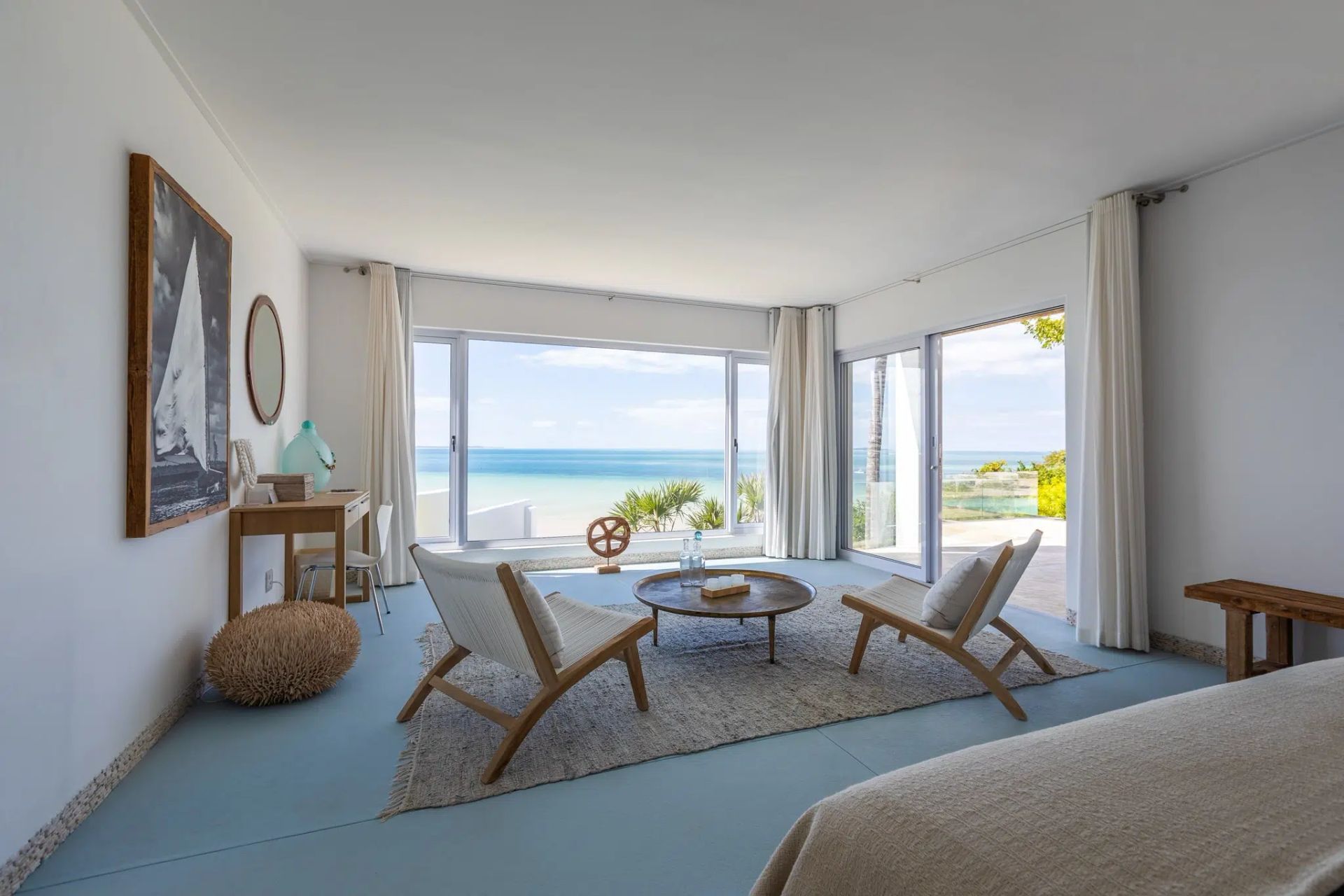 Bright living room with ocean view, large windows, and two lounge chairs on a rug.