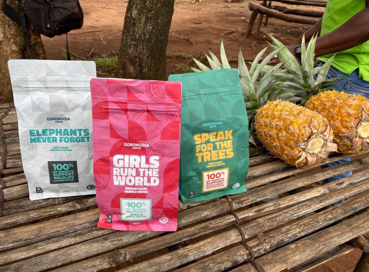 Colorful coffee bags on a wooden bench beside two pineapples outdoors