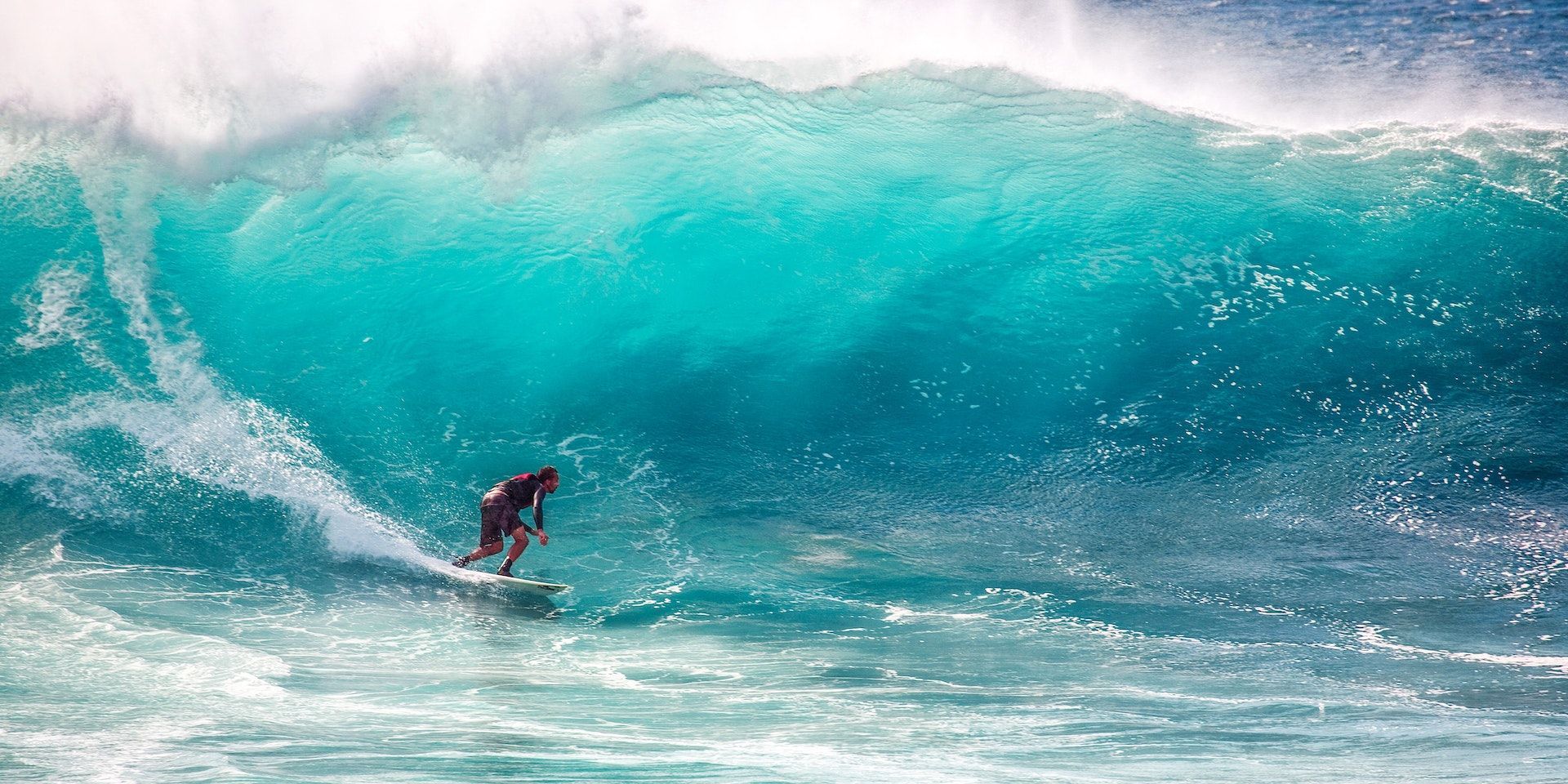 Surfer riding a large turquoise wave