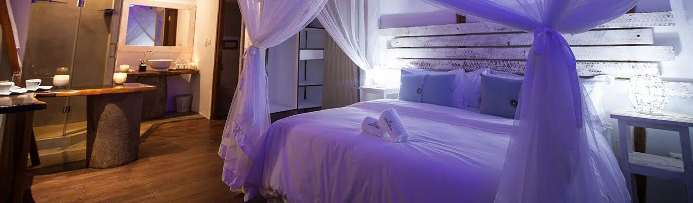 Romantic bedroom with a four-poster bed, purple drapes, and warm ambient lighting