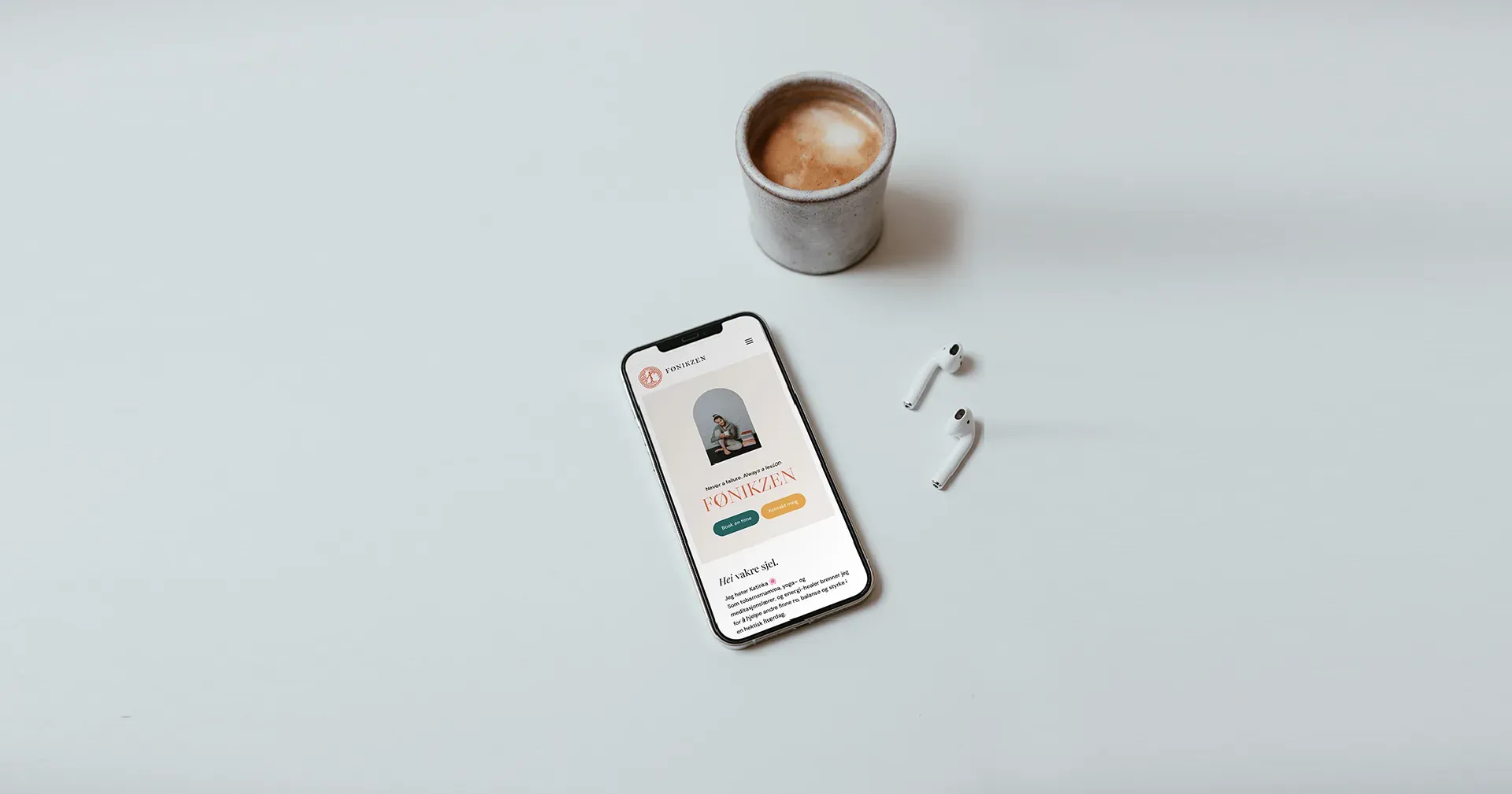 Smarttelefon som viser app, med kaffe og ørepropper på en lys overflate.