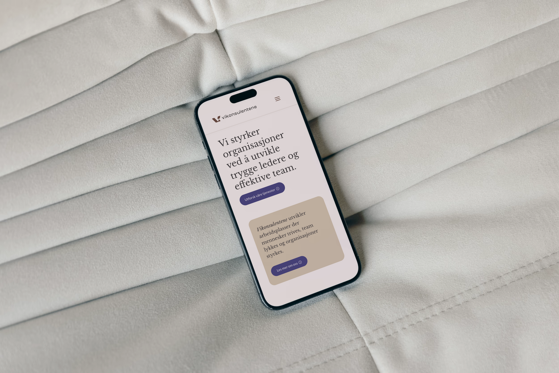 Nærbilde av Iphone som ligger på en pute med nettside for Vikonsulentene.