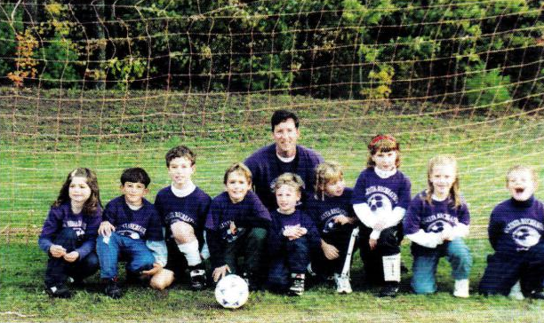 A group of children are posing for a picture with a soccer ball