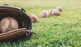 A baseball glove with a baseball in it is laying on the grass.