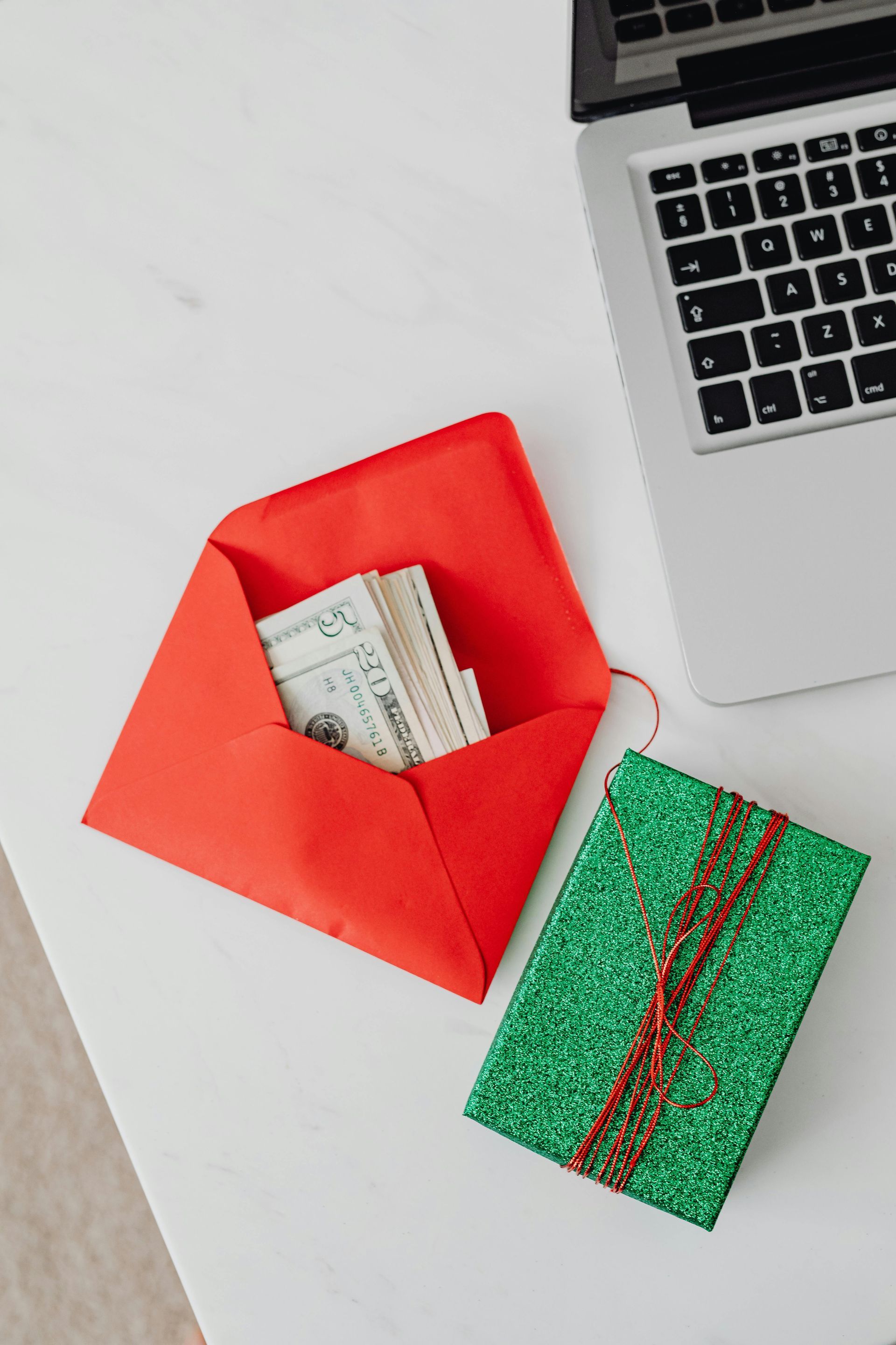A red envelope filled with money next to a laptop.