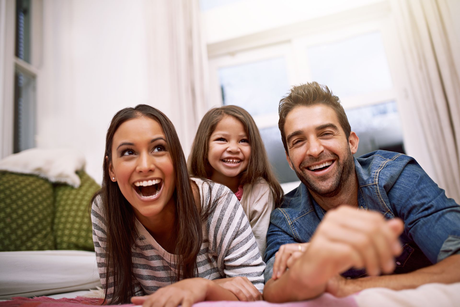 A family is laying on a bed laughing while watching tv.