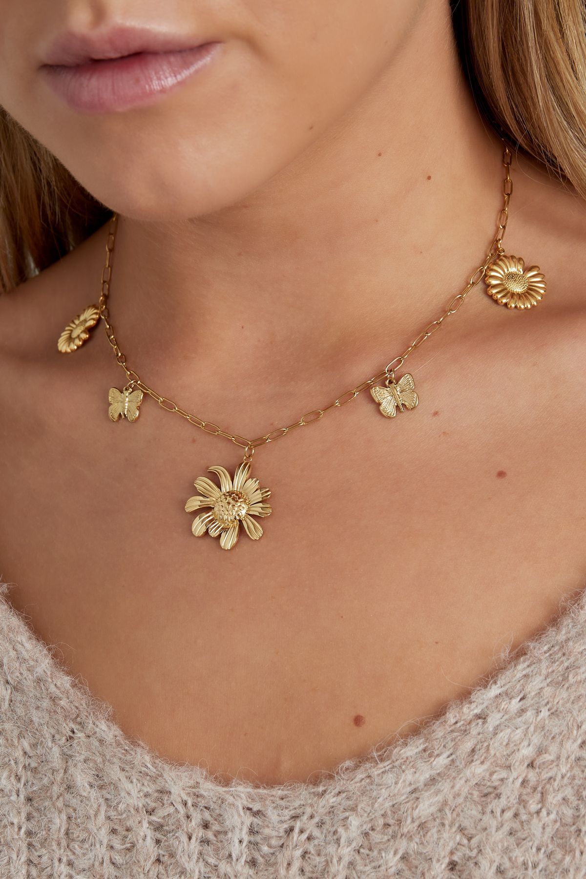 Een zilveren ketting met bloemen en vlinders aan een ketting.