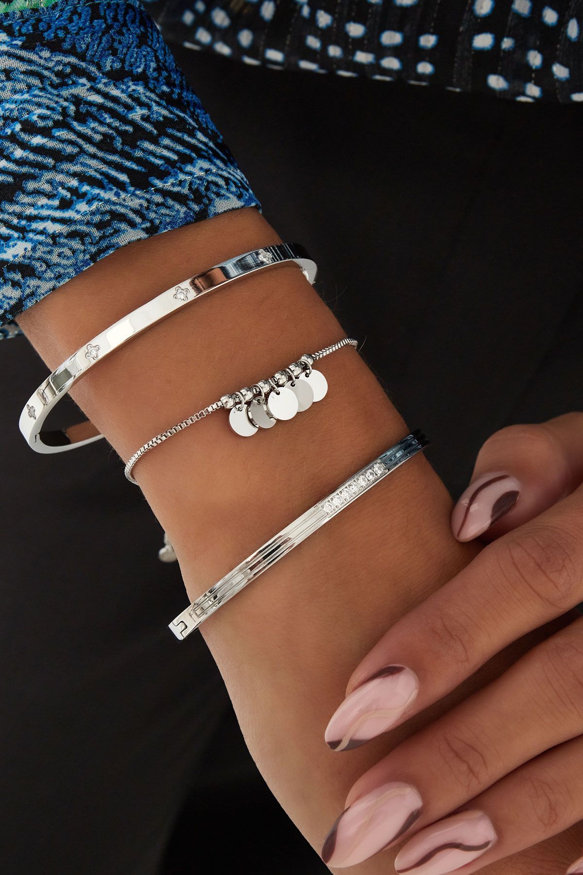 Een vrouw met drie zilveren armbanden om haar pols