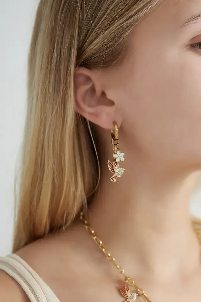 Een close-up van een vrouw met oorbellen en een ketting.