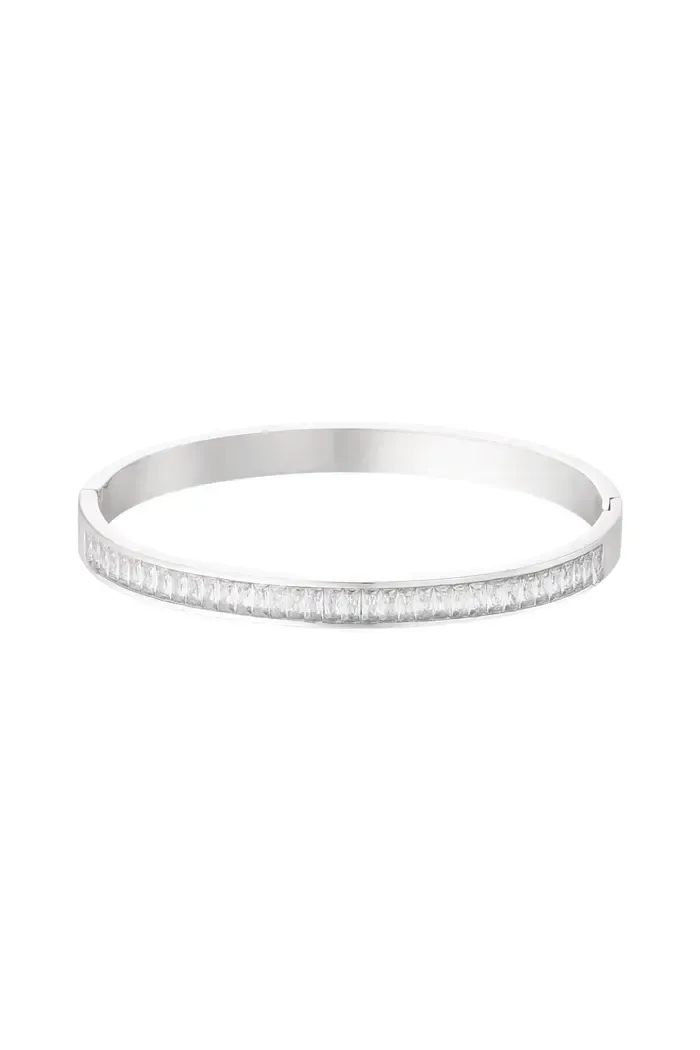 Een zilveren armband met diamanten op een witte achtergrond.
