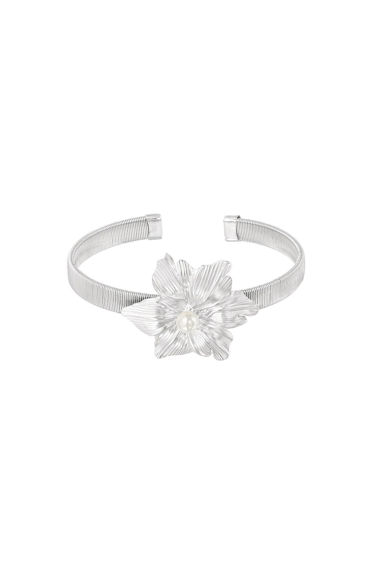 Een zilveren armband met een bloem erop op een witte achtergrond.