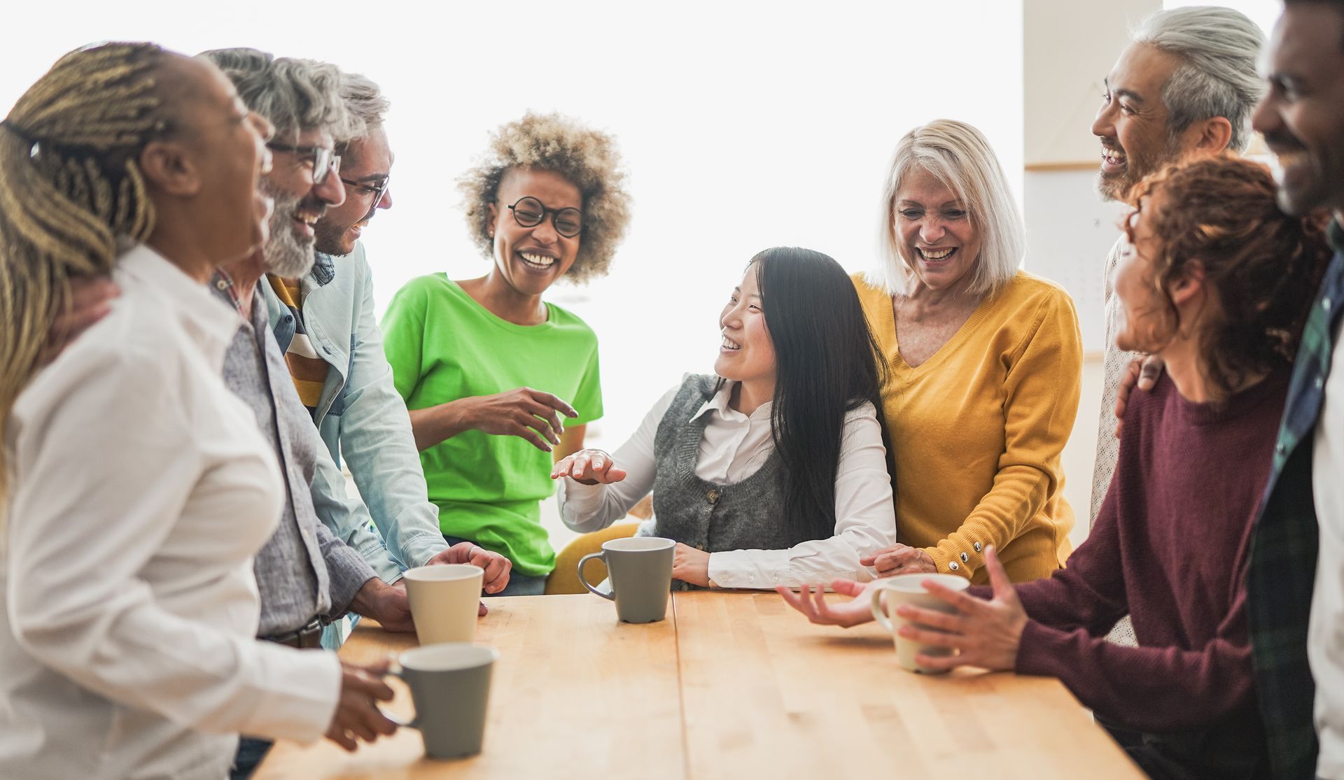 Group chatting around a table with coffee cups in a bright meeting room