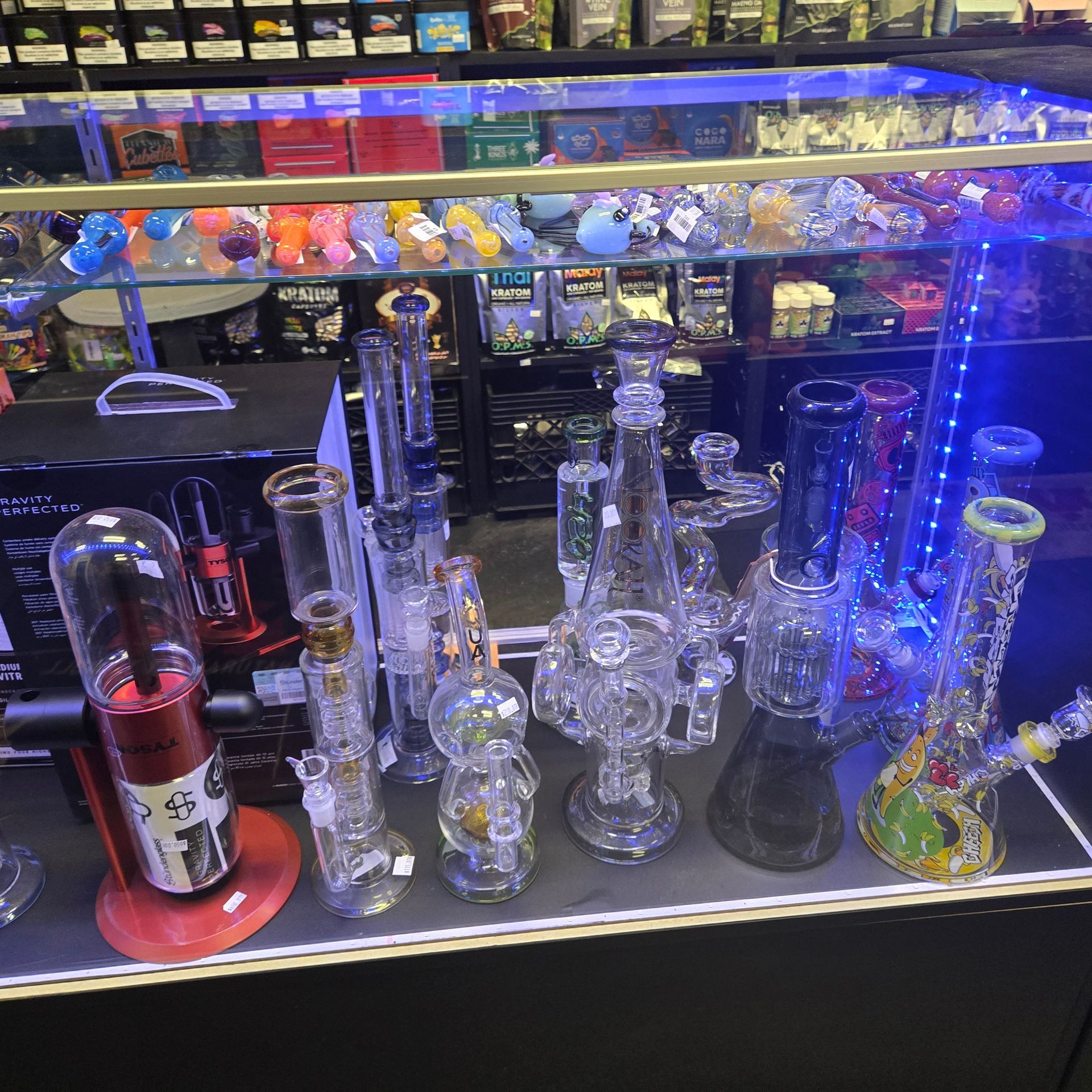 Colorful glass pipes and two small figurines on a shelf in dim lighting