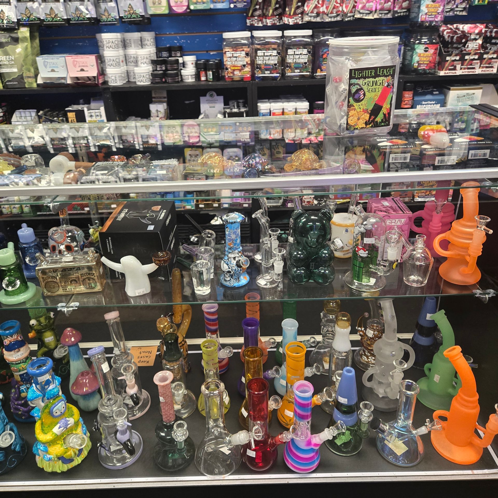 Small vape shop interior with tables, stools, wall art, neon signs, and a counter display.