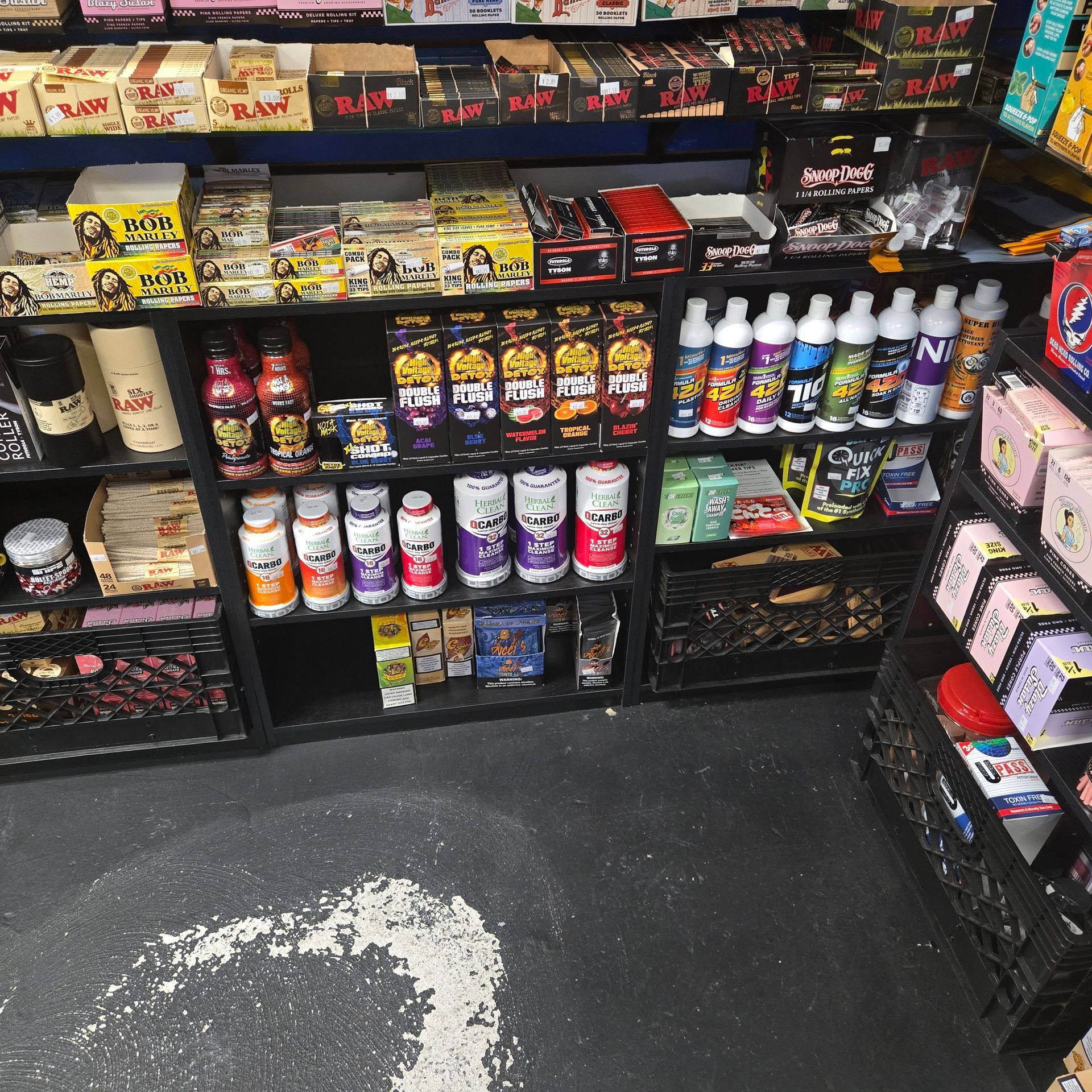 Small vape shop interior with tables, stools, wall art, neon signs, and a counter display.