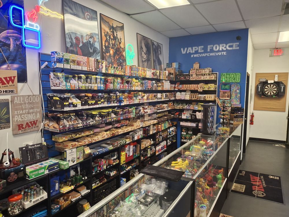 Convenience store vape aisle with shelves of colorful products and a “VAPE FORCE” sign on the wall
