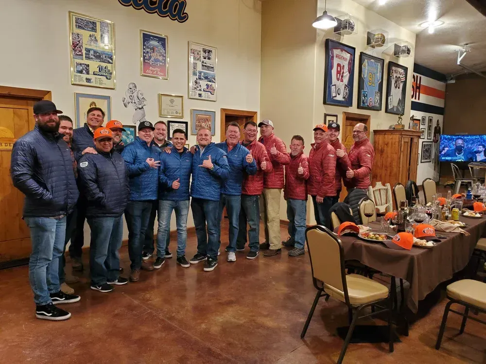 Group of people in blue and red jackets standing in a restaurant, posing for a photo.