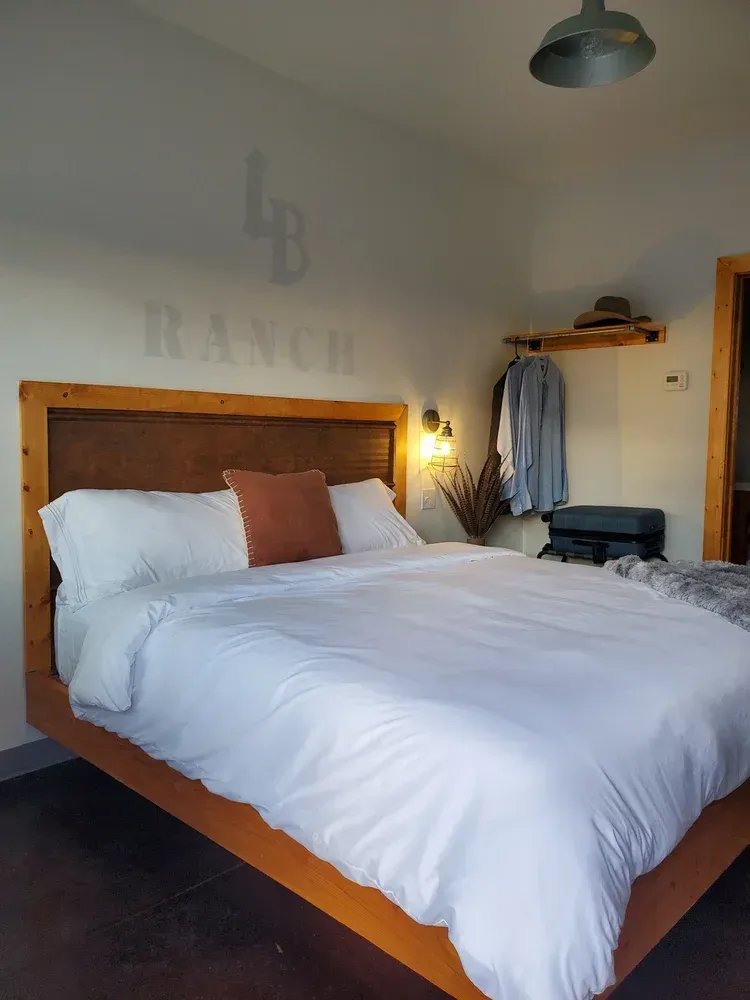 Cozy bedroom with a wooden bed, white bedding, and wall art in a softly lit room