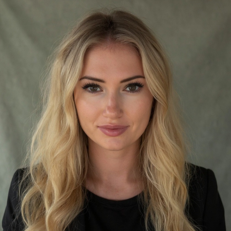 Portrait of a blonde woman in a black top against a gray backdrop